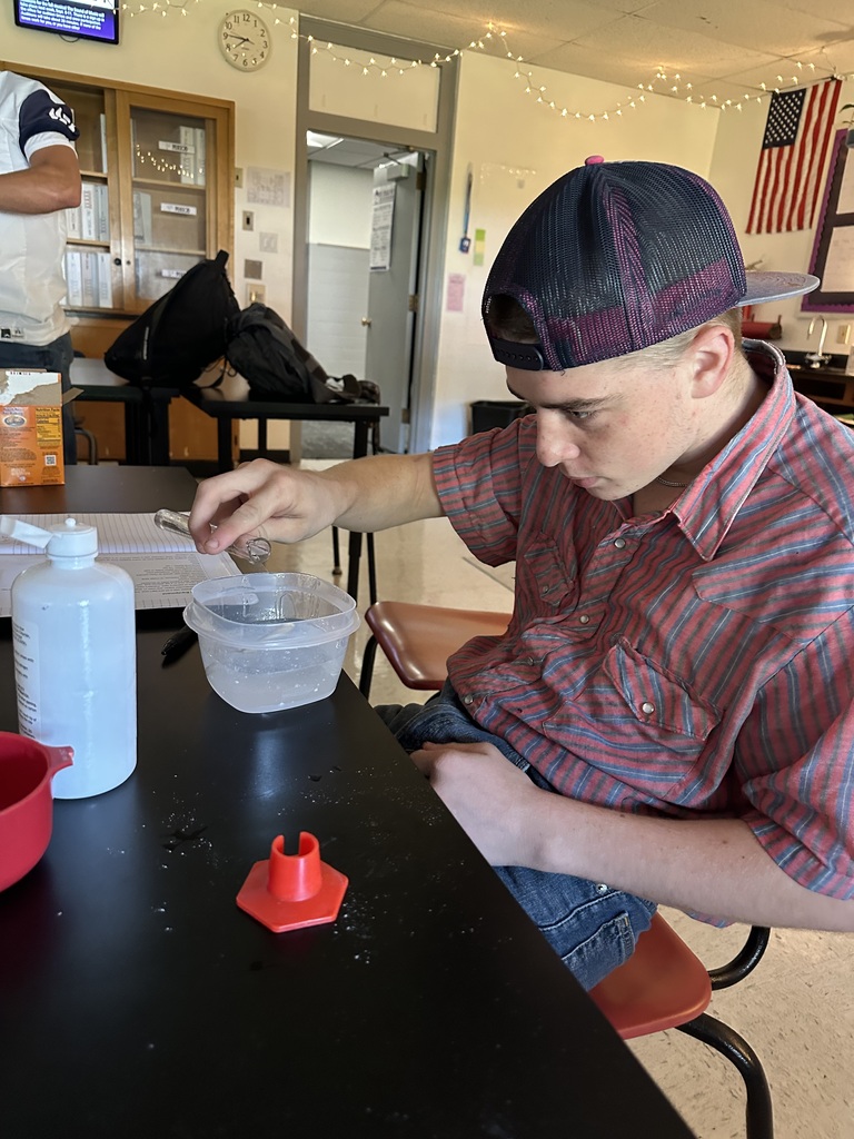 Student pouring in contact solution to glue as part of his slime mixture.
