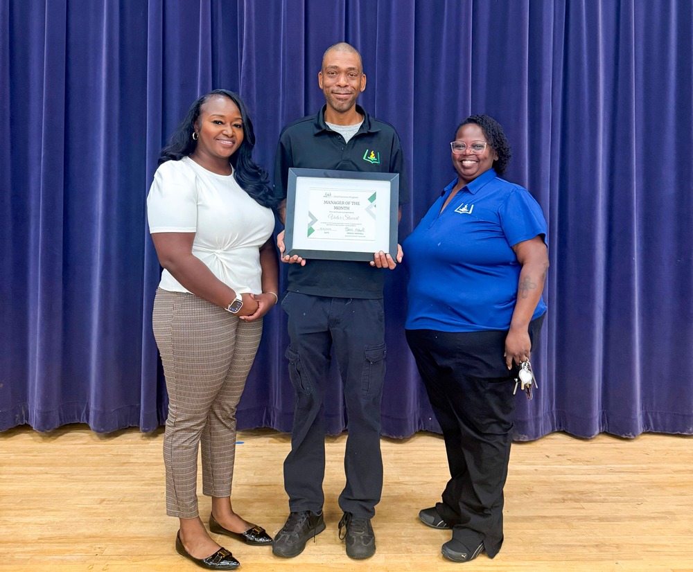 Child Nutrition Manager Victor Stewart holds a certificate and stands with Child Nutrition Resident District Manager Ebonee Maxwell and Child Nutrition Field Supervisor Bonita Williams