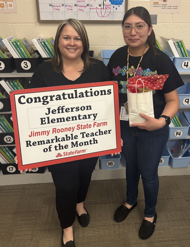 An image of two women, one holding a sign and another holding an award.