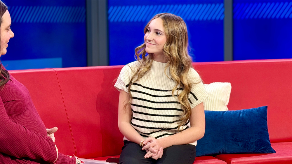 Student conducting an interview sitting on a red couch.
