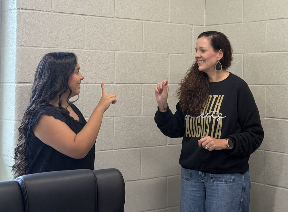 Two women practice sign language.