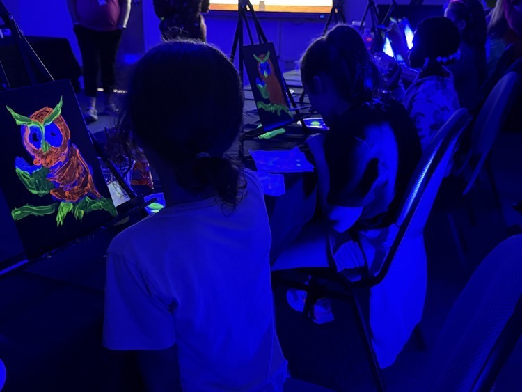 Young students paint glow-in-the-dark owls.