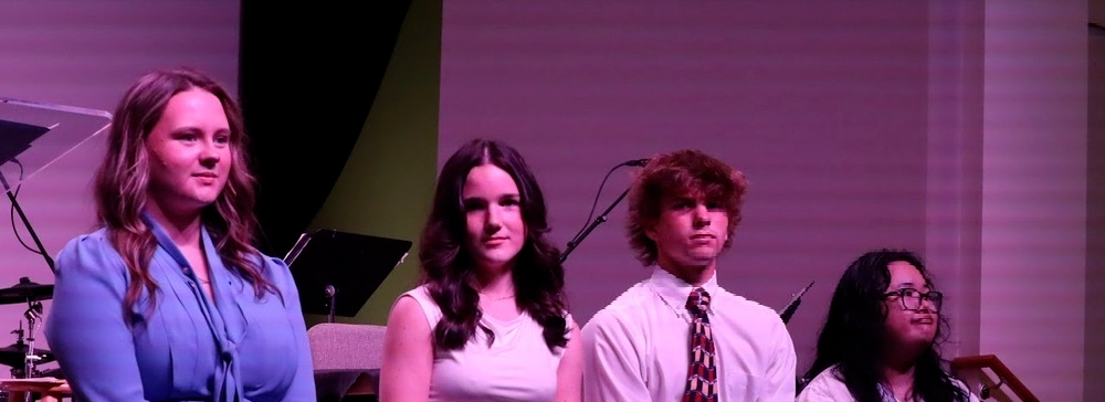 South Aiken High School speech and debate students stand on stage during showcase.