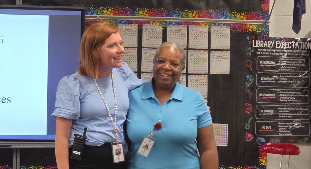 Two women smiling with arms around each other.