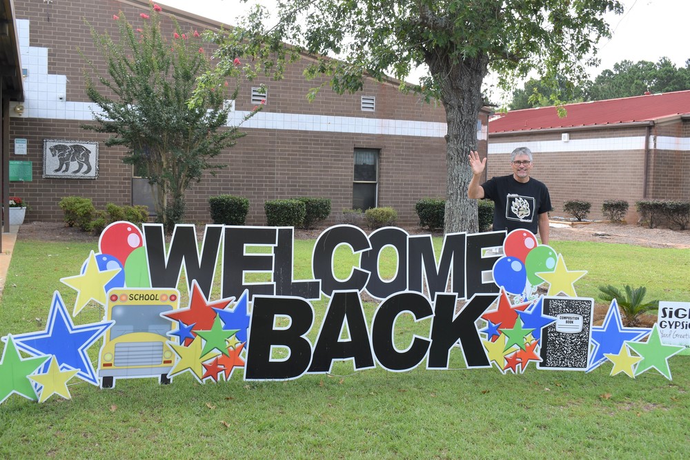 Man standing behind sign that says "Welcome Back".