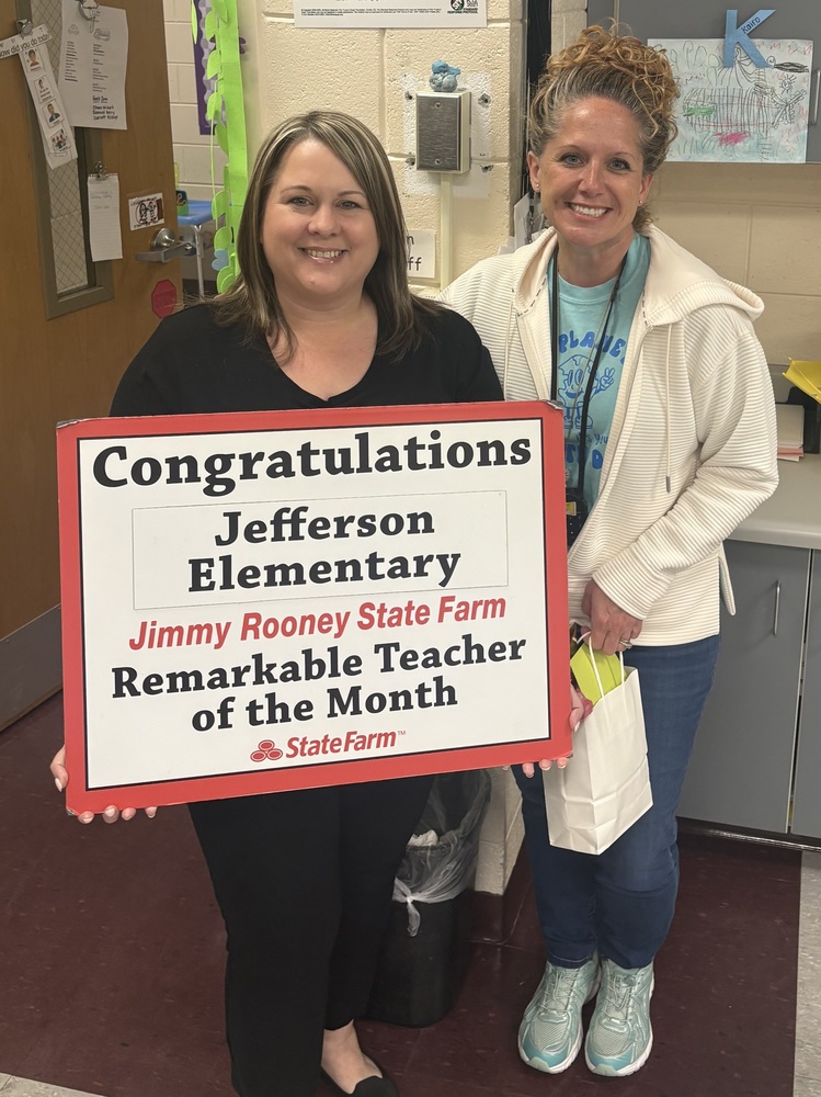 An image of two woman, one holding a sign and another holding an award.