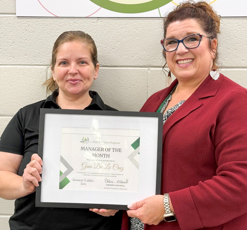 Child Nutrition Manager Gina De La Cruz with Child Nutrition Coordinator Polly Peyinghaus holding an employee of the month certificate