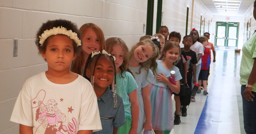 Students smile in a single file line.