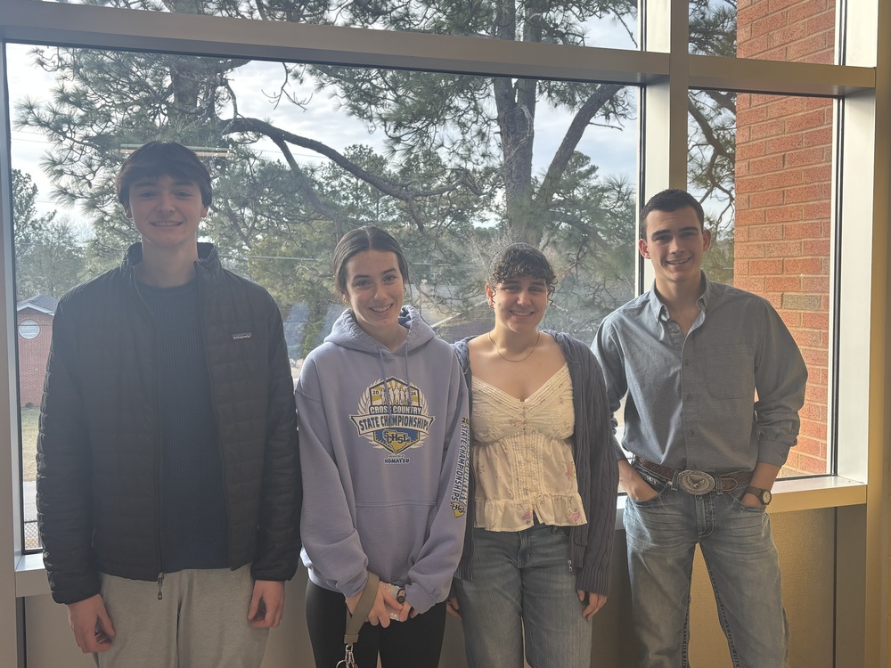 Four students standing in front of a window
