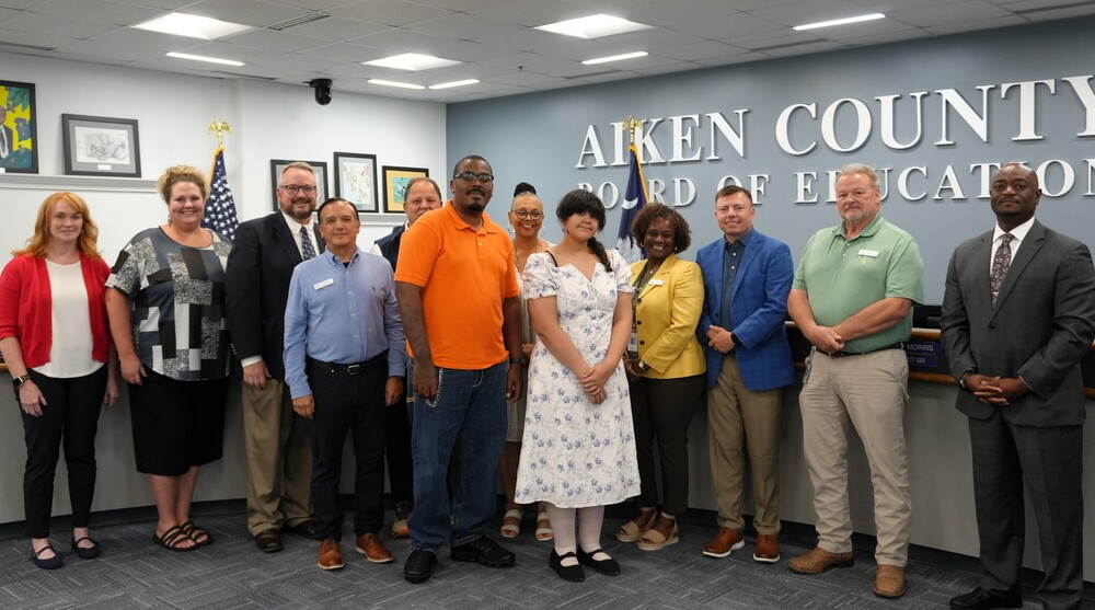 Jackson Middle School student is honored by the ACPSD School Board while posing for a picture with the student and her parents along with school staff.