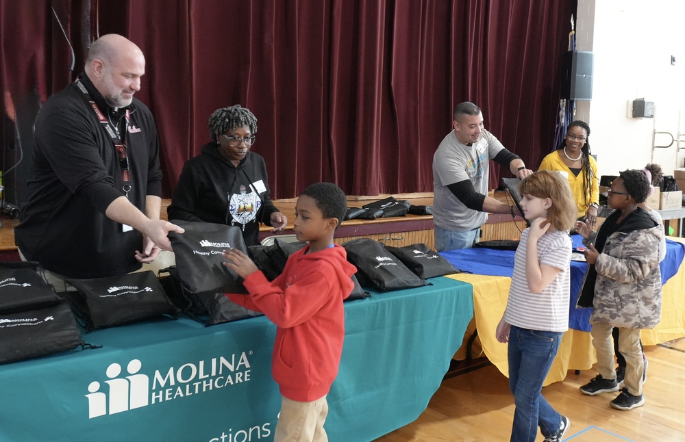Adults handing children bookbags