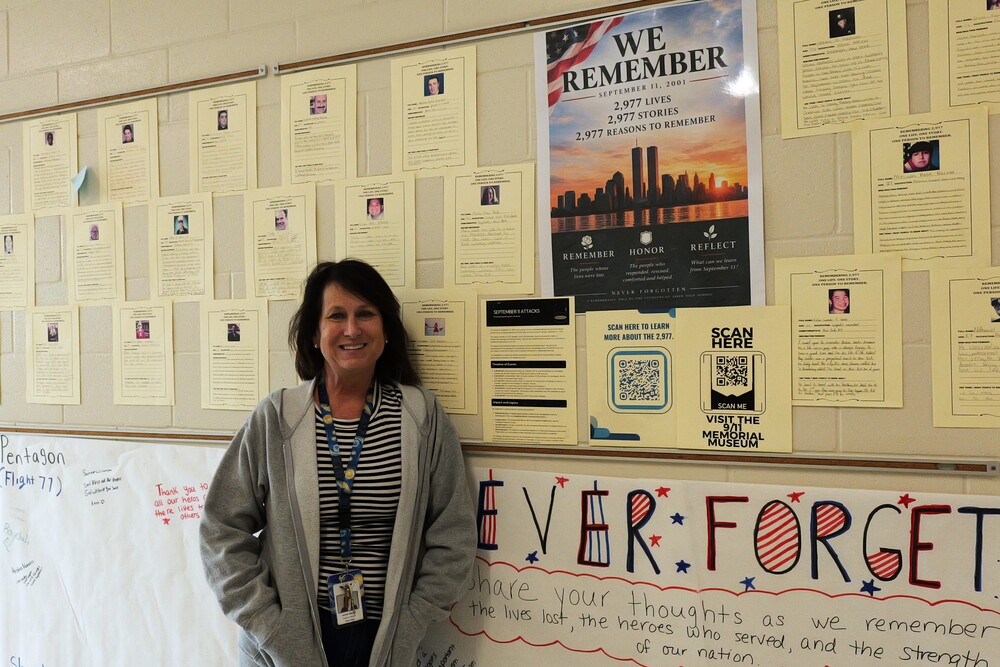 Aiken High School teacher poses next to 9/11 remembrance wall.