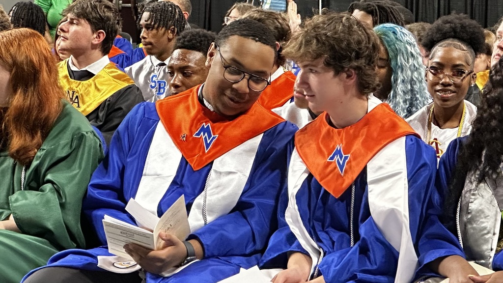 Two CTE Completers in Orange and Blue Robes representing Midland Valley talk at the ceremony.