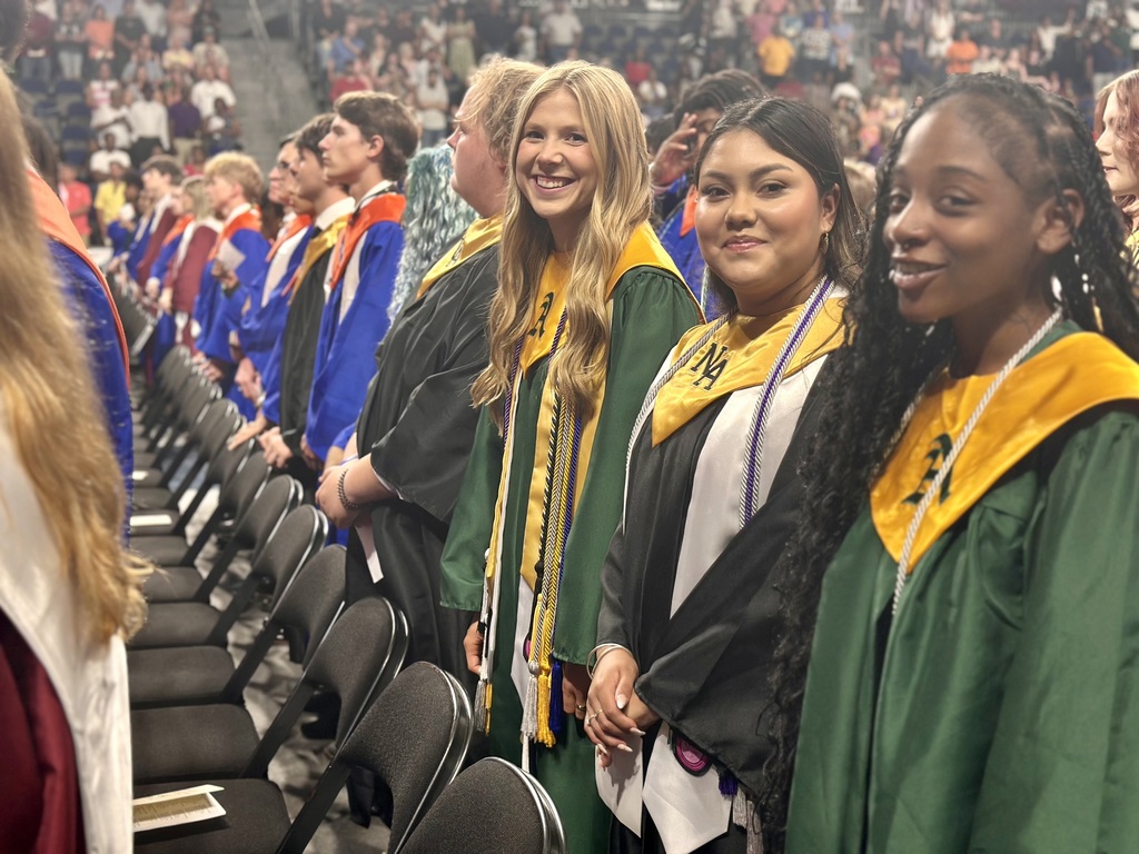 Three girls smile in green and gold robes, representing Aiken High.