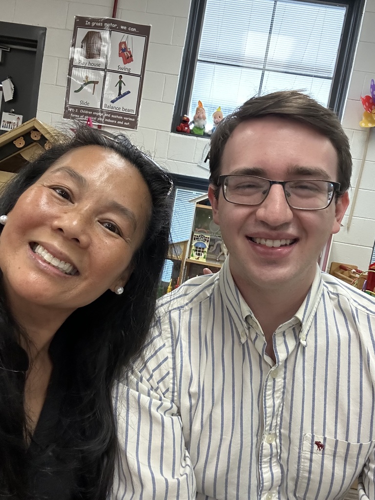 Two teachers in a classroom smiling.