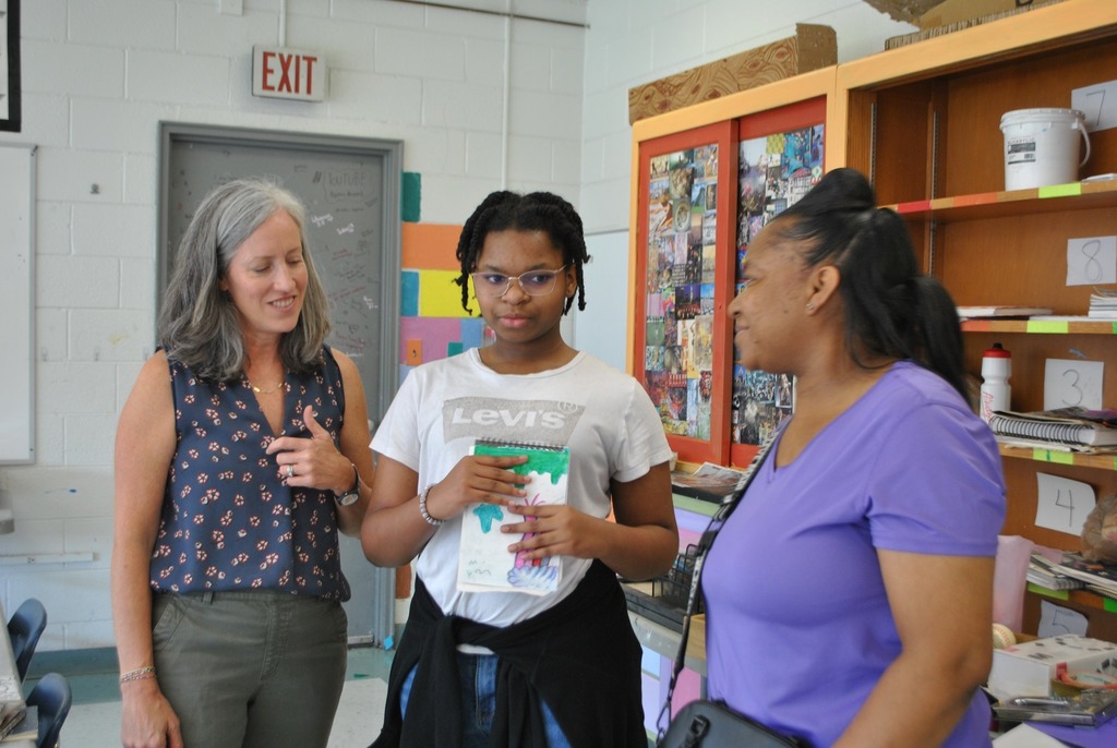 Art teacher speaking with a parent and student during Walk the Schedule event.