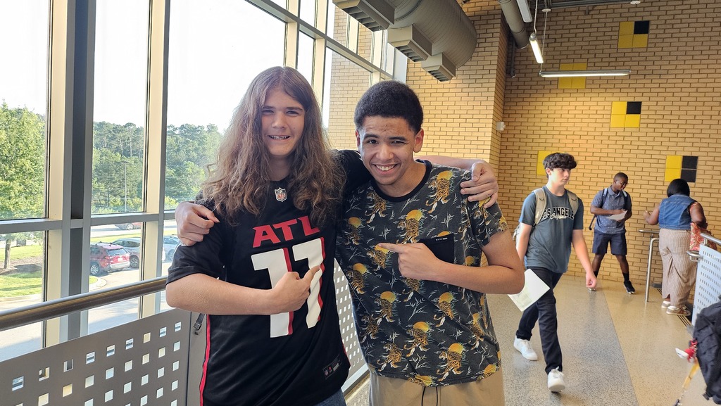2 Boys in hallway pointing at one another. 