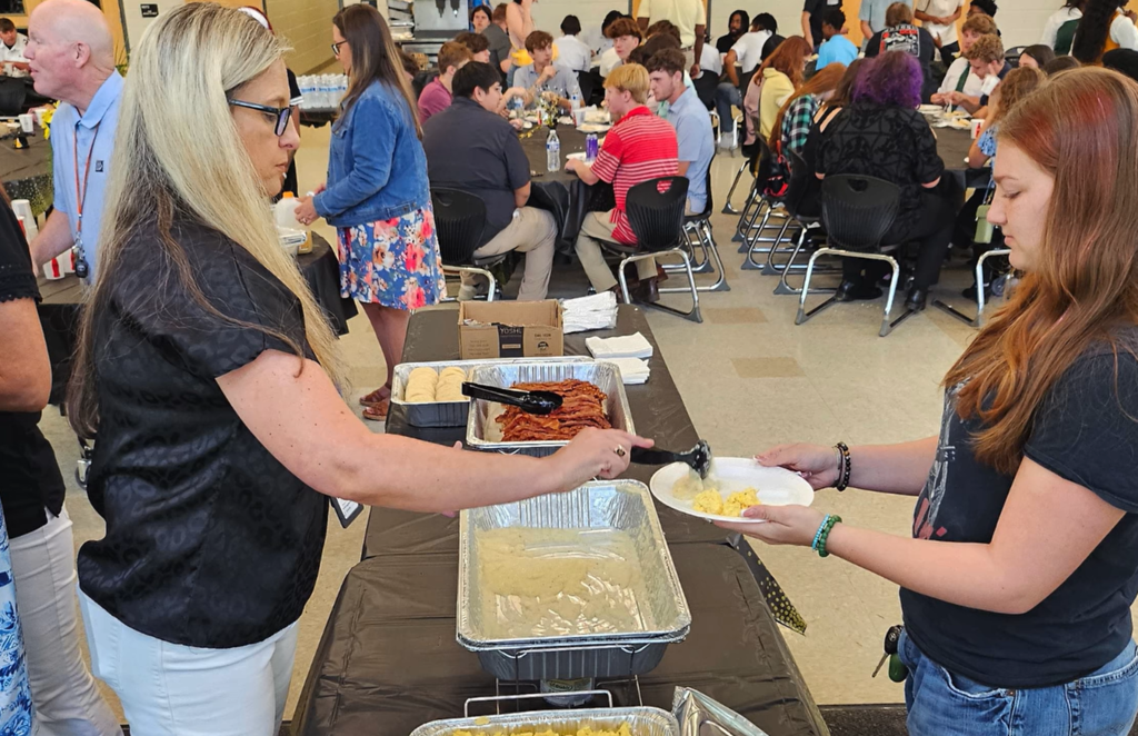 Student being served breakfast in cafeteria. 
