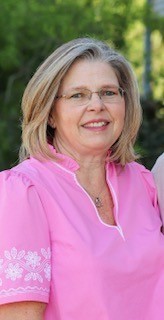 Lady smiling in a pink top.