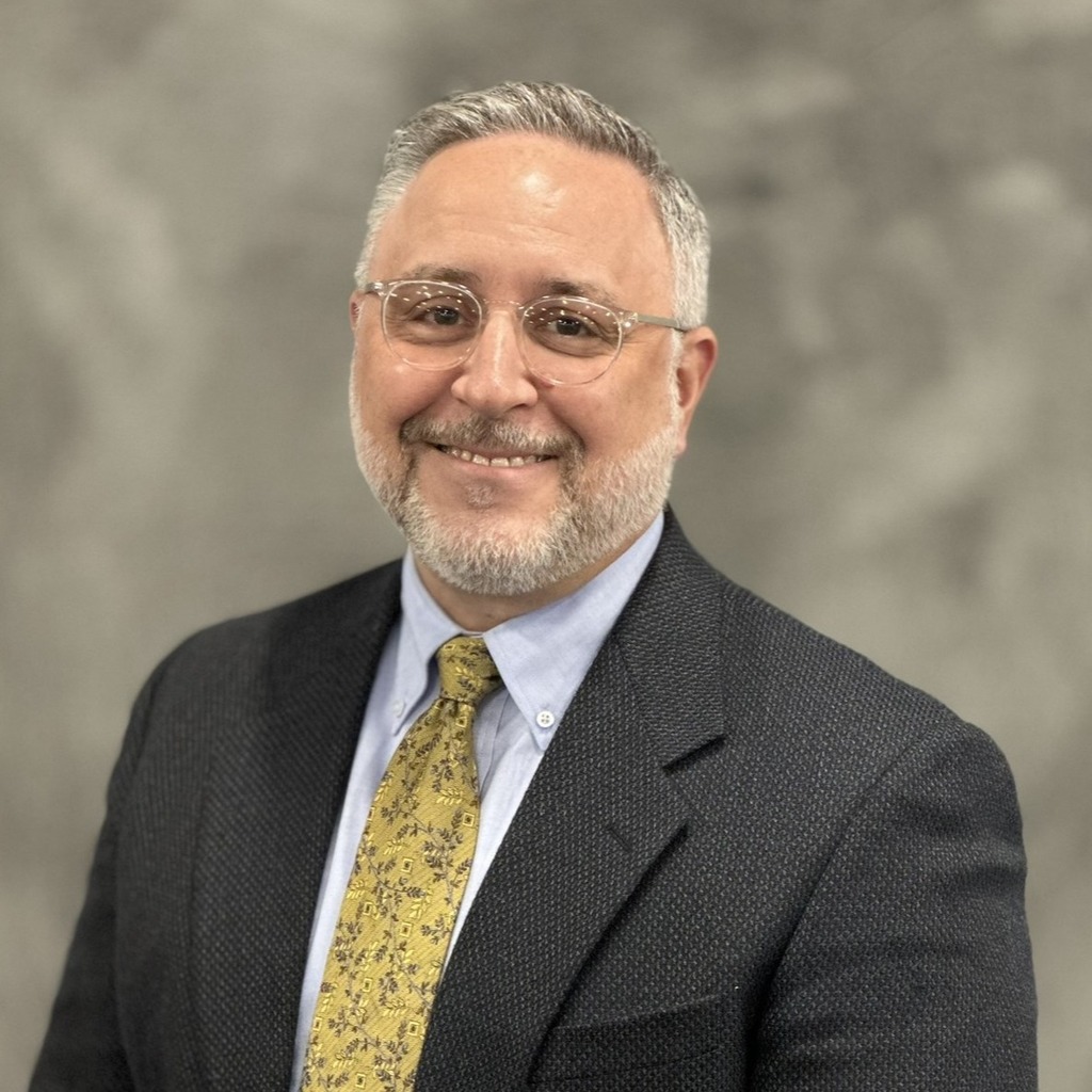 Smiling man in a suit with a yellow tie.