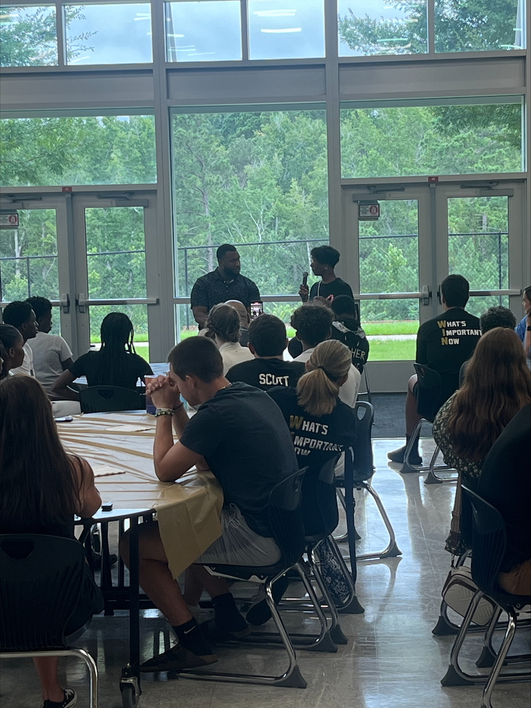 NAHS Alumni and his mom speaking in front of moms and son football players in cafeteria. 