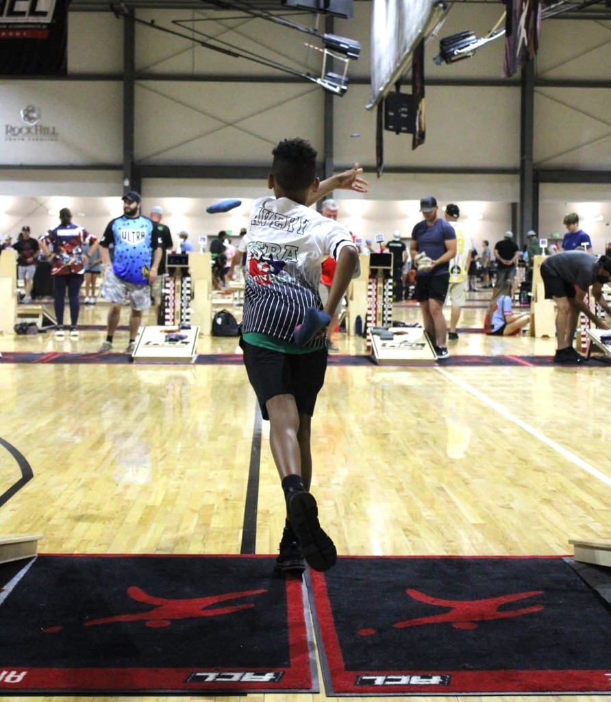 Boy throwing  cornhole bags.