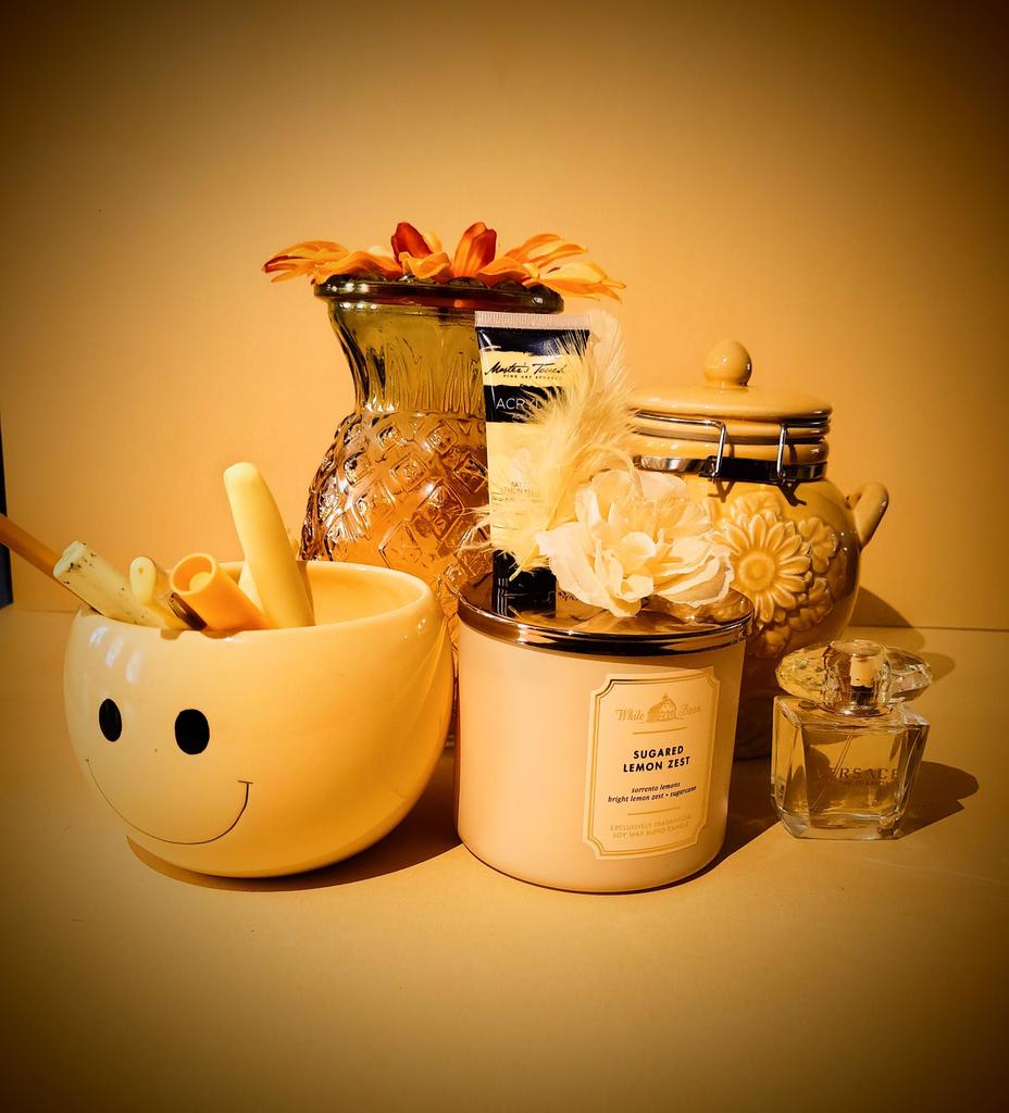 Yellow based pho9to with happy mub, pens, markers, highlighted,candle flowers performance, and yellow vase and cookei jar. 