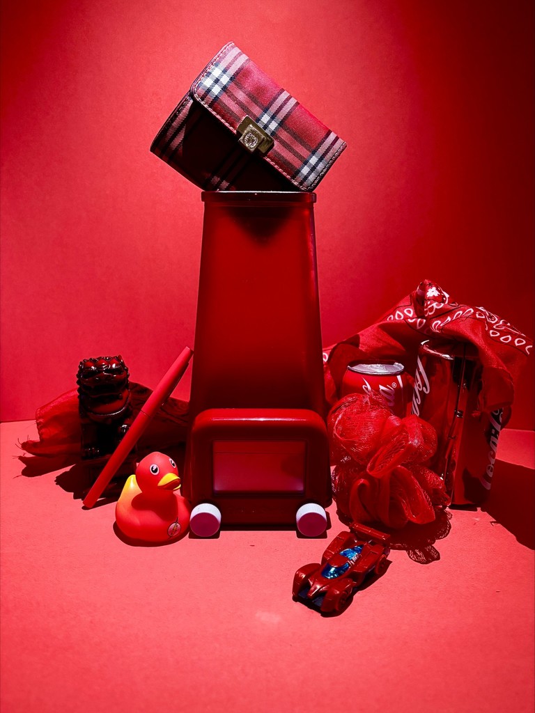 Red based photo with red race car, duck, etch a sketech, dinosaur, loofa, and coke can and scarf.