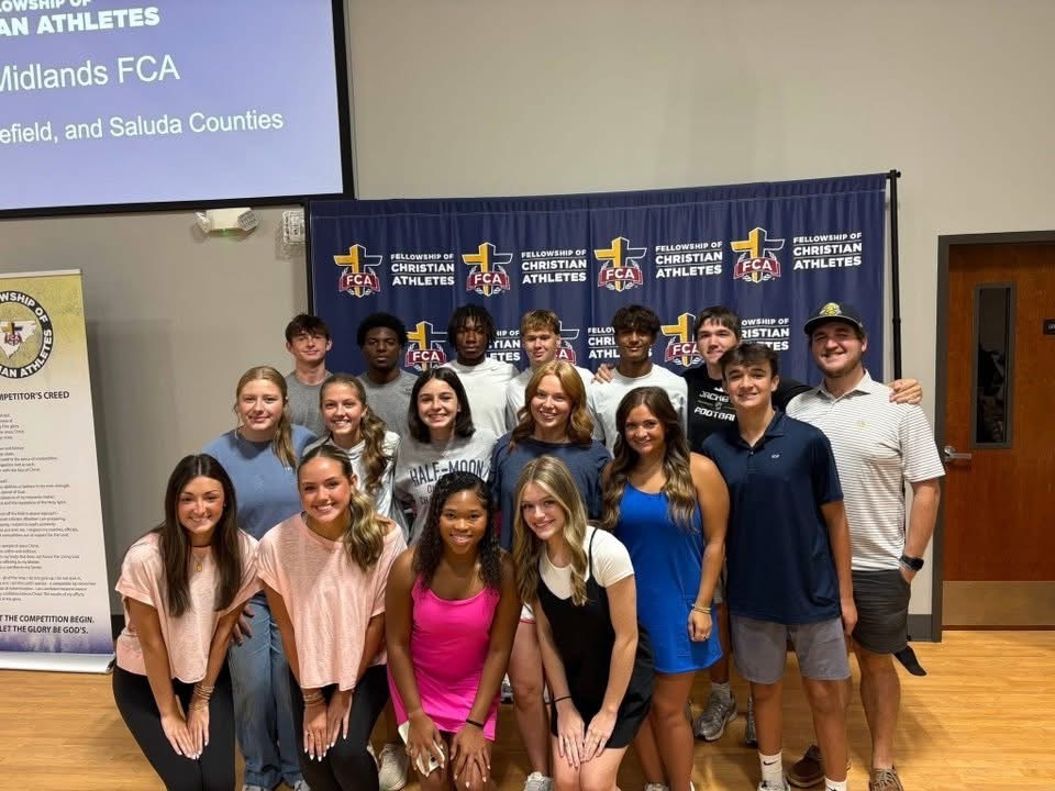 Students posing in front of Fellowship for Christian Athletes. 