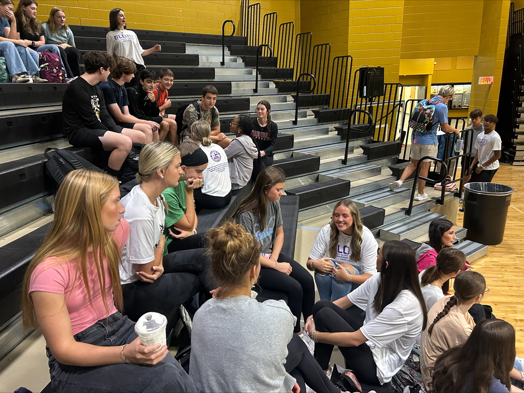 Students sitting on bleachers talking with one another. 