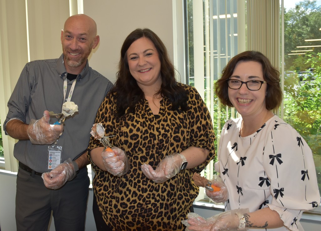 3 smiling people holding icecream scoops. 