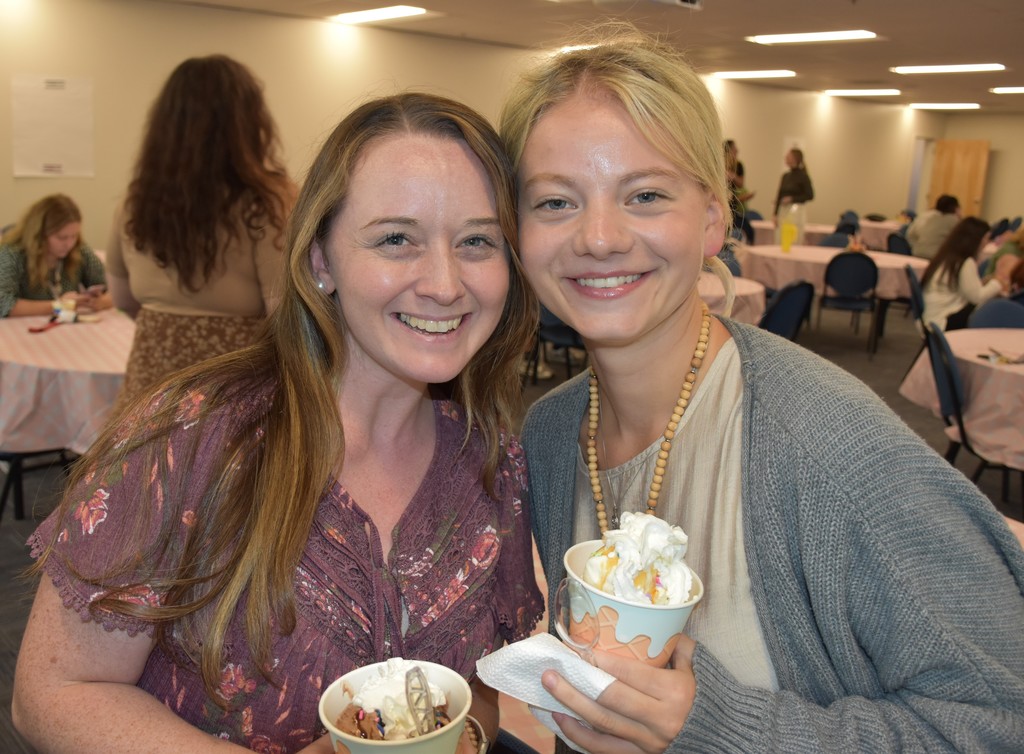 2 smiling teachers holding bowls of icecream.
