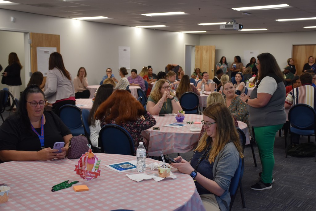 Room full of new teachers sitting around round tables.