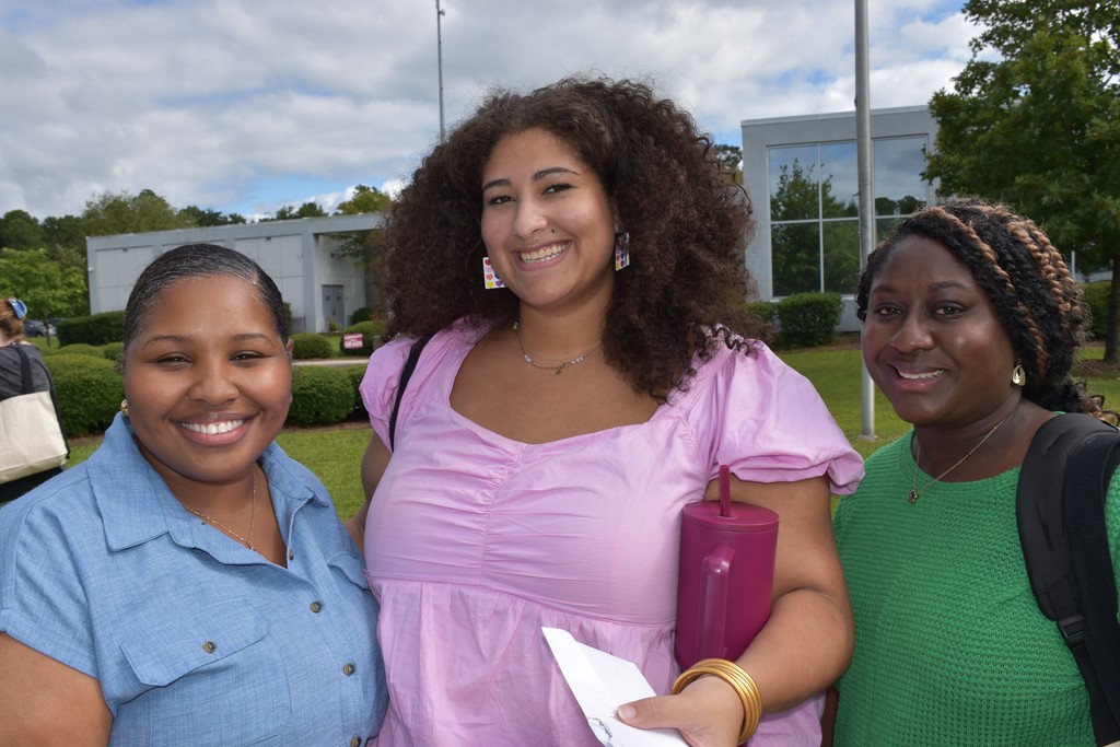 3 smiling teachers in front of a building.