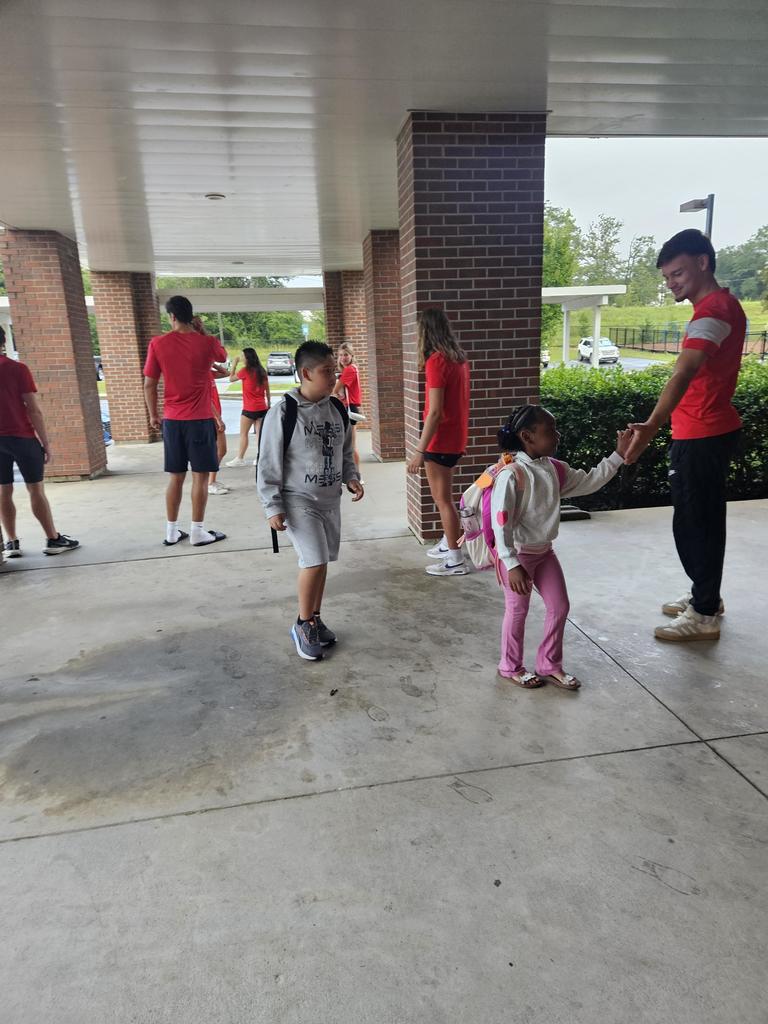 college athletes high fiving elementary students at carline