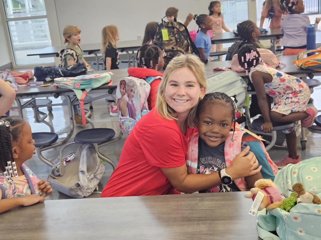 a young woman hugging a kindergarten student in the cafeteria