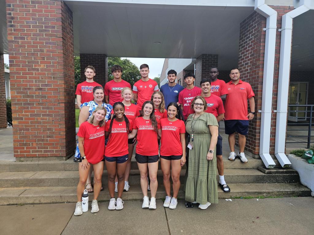 a group of college athletes posing with the school principal