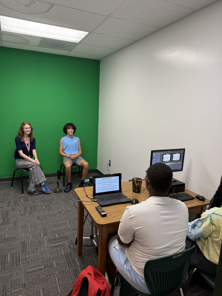 2 students sitting in front of green screen and 2 students sitting in front of computers