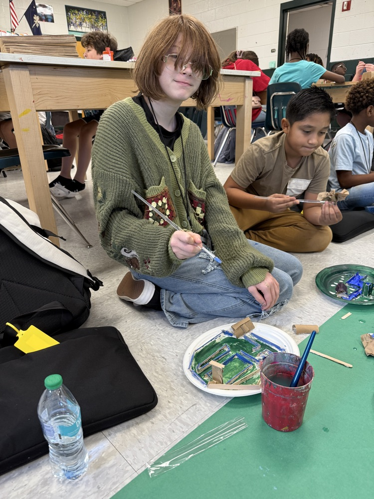student painting and smiling at camera 