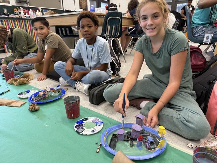 students painting and smiling at camera 