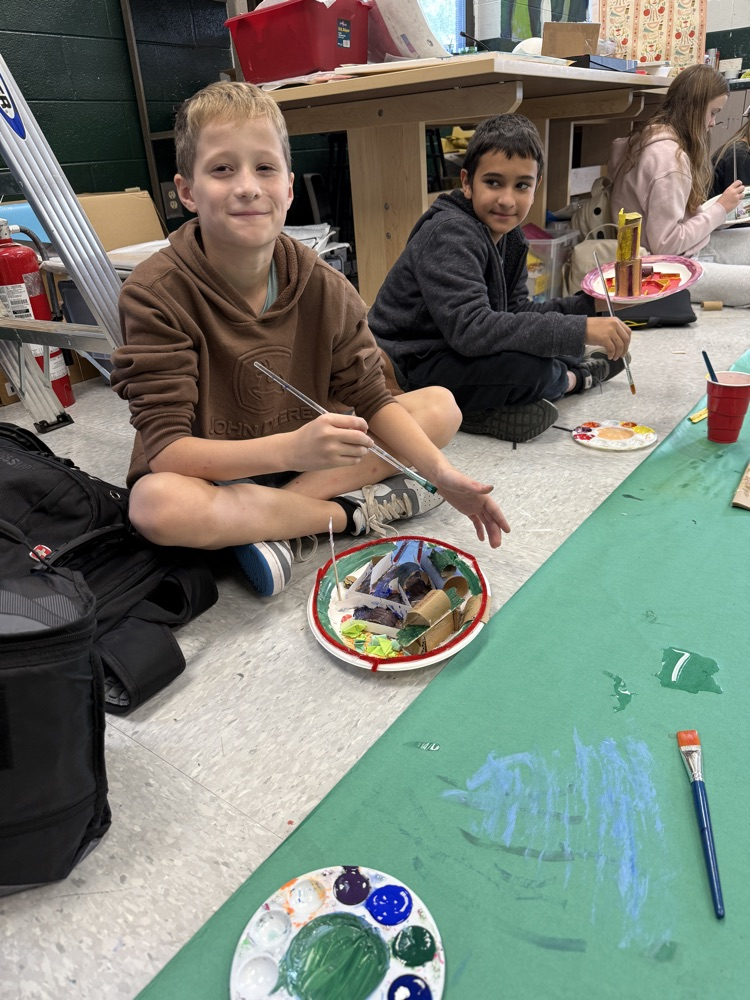 students painting and smiling at camera 