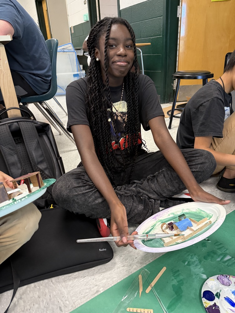 student painting and smiling at camera 