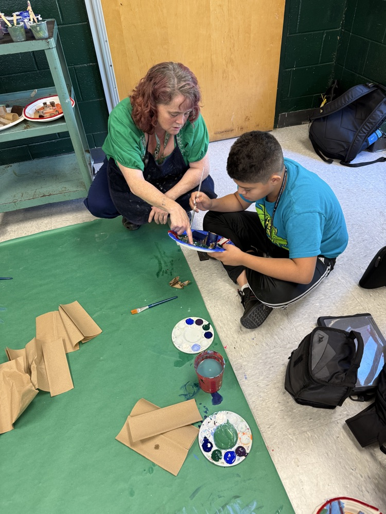teacher helping student paint 