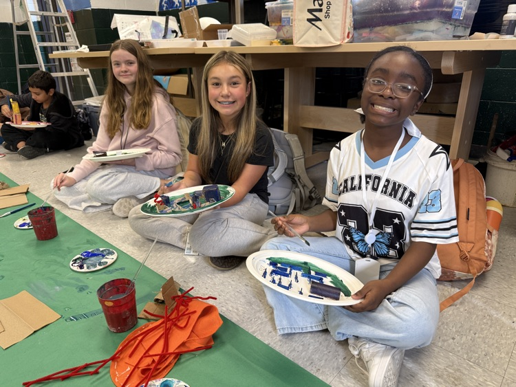 students painting and smiling at camera 