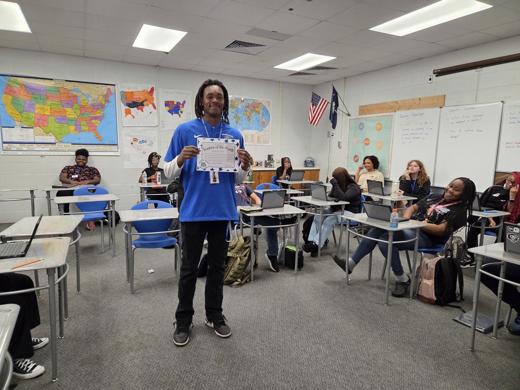 Ja'Kobe Bush, August Teacher of the Month, standing in front of his students with a certificate.