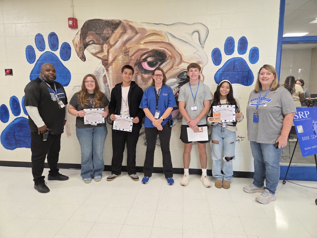 August Students of the Month posing in front of bulldog mural with admin