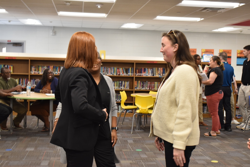 Teachers and principal standing in library.
