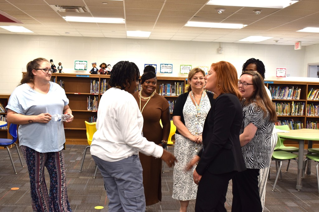 Teachers and principal standing in library.