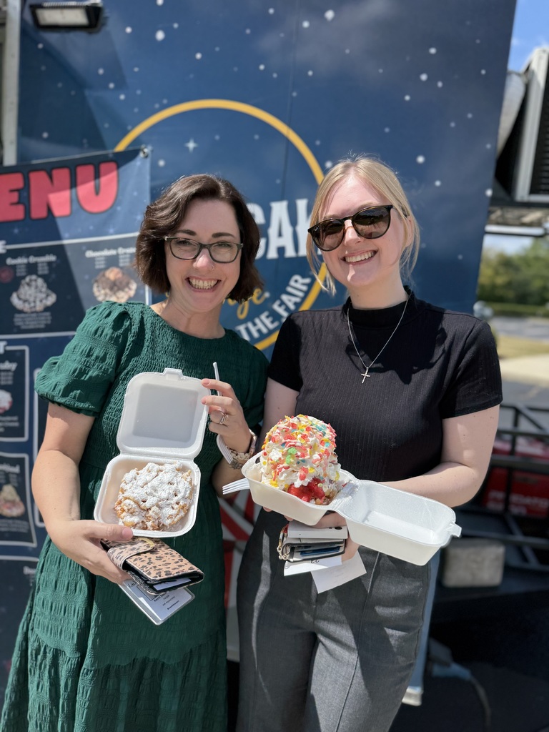 Two ACPSD staff with funnel cakes outside a food truck.
