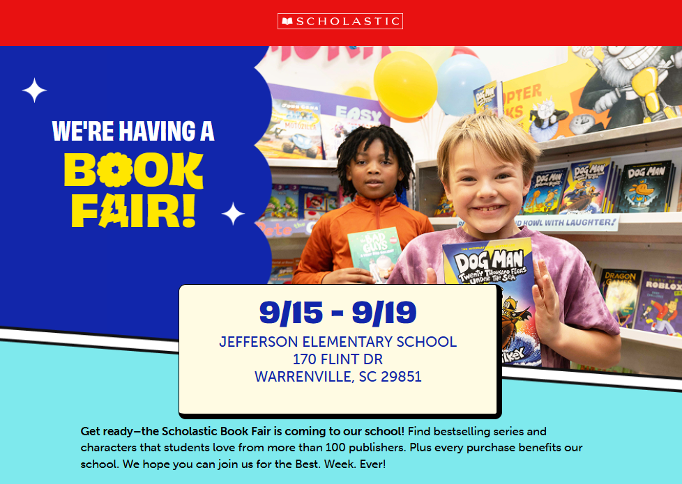 Two children stand holding a book in front of a display of books.